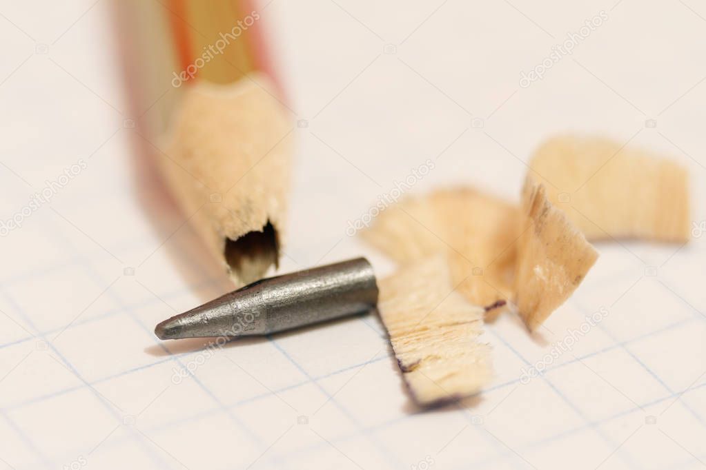 Sharpened pencil with a broken tip over a blank sheet of paper