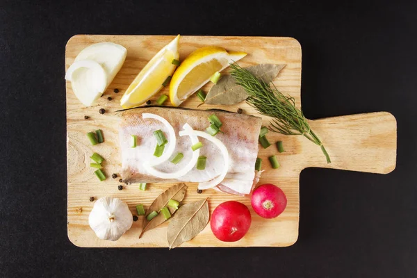 Ocean fish meat and organic radish, lemon, onion and spice on cutting board. Natural, organic ingredients for healthy and diet food. Top view