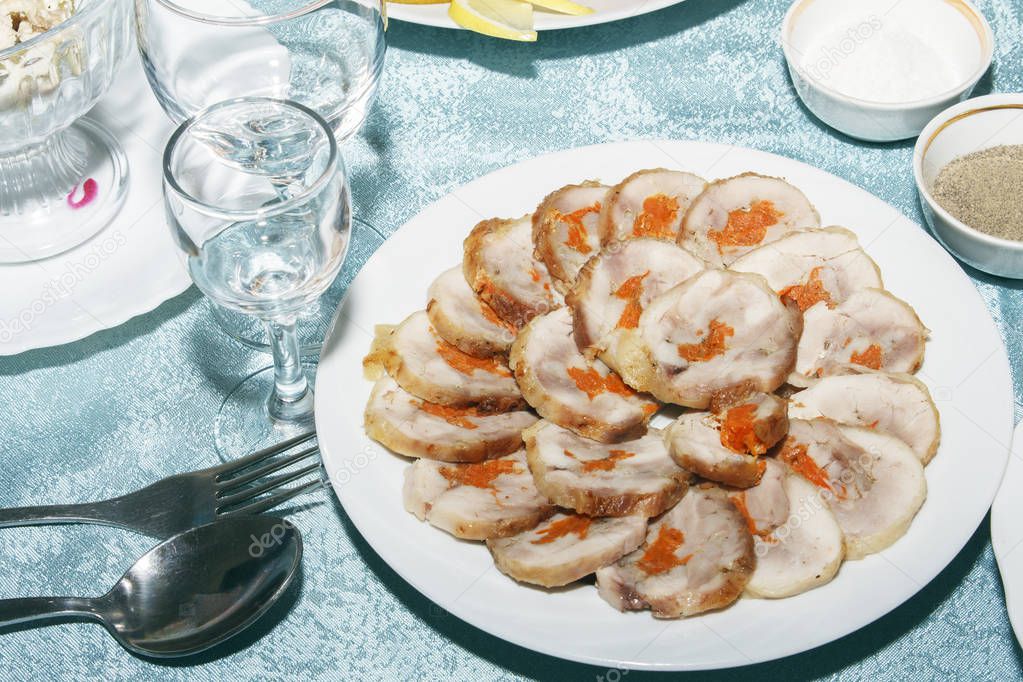 Table served with roll of poultry meat with vegetables filling. Empty clean wine glasses and delicious cold snack on festive table