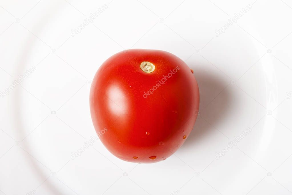 Red ripe whole tomatoes on white plate closeup. Healthy food concept. Top view.