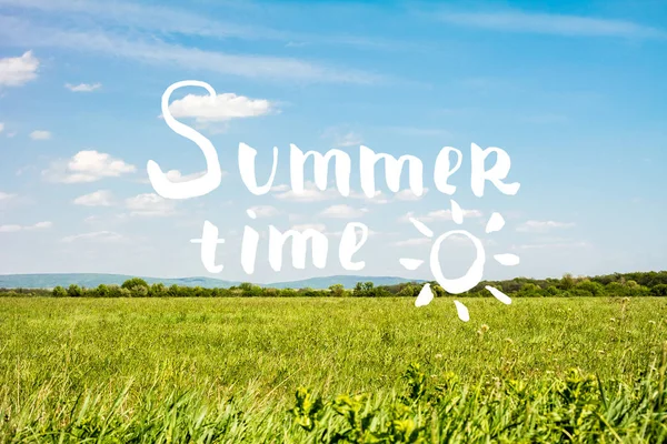 Summer time lettering with sky and grass background.