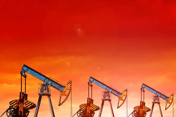 Αντλίες πετρελαίου στο ηλιοβασίλεμα. Πορτοκαλί ουρανό. — Φωτογραφία Αρχείου