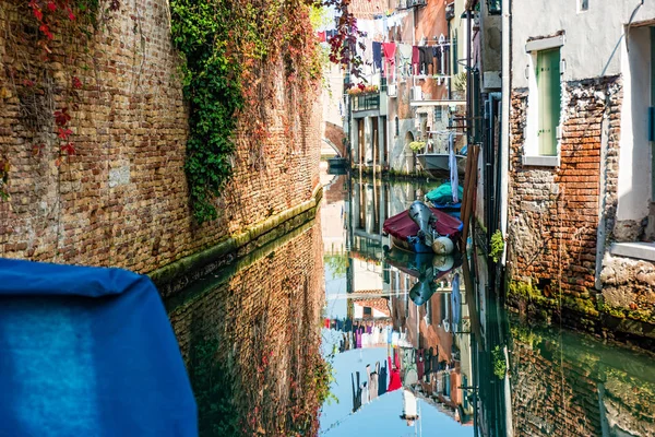 Rua de canal tradicional com reflexo na lavanderia de água pendurada fora de uma fachada típica veneziana. Itália — Fotografia de Stock