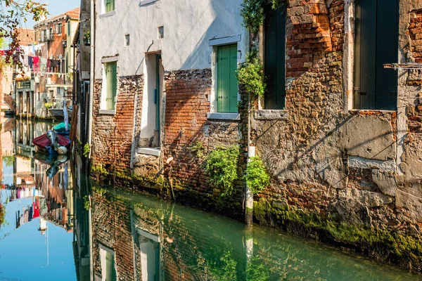 Rua de canal tradicional com reflexo na lavanderia de água pendurada fora de uma fachada típica veneziana. Itália — Fotografia de Stock