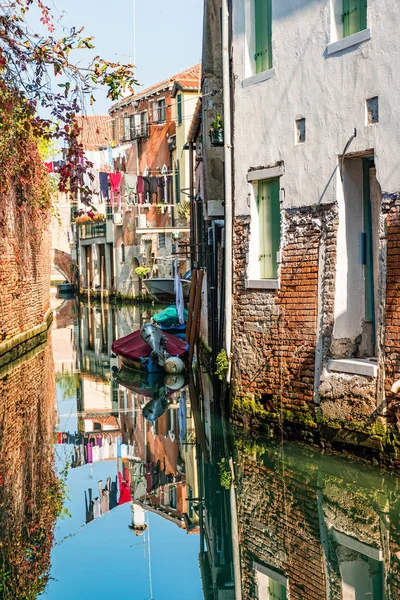 Rua de canal tradicional com reflexo na lavanderia de água pendurada fora de uma fachada típica veneziana. Itália — Fotografia de Stock