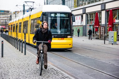 Berlin, Almanya - Aralık 2019: Berlin 'de sokak hayatı. Şık giyimli bir adam tramvayın yanında bisiklet sürüyor..