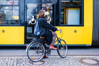 Berlin, Almanya - Aralık 2019: Berlin 'de sokak hayatı. Şık giyimli bir adam tramvayın yanında bisiklet sürüyor..