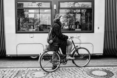 Berlin, Almanya - Aralık 2019: Berlin 'de sokak hayatı. Şık giyimli bir adam tramvayın yanında bisiklet sürüyor..