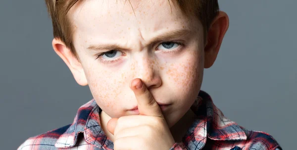 Frunciendo el ceño descarado niño pequeño con pecas teniendo una mirada sucia — Foto de Stock