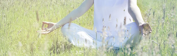 Руки молодой женщины, медитирующей в позе йоги на траве — стоковое фото