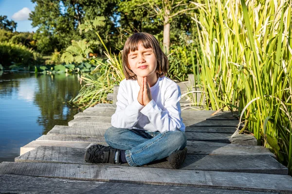 Peaceful young yoga child enjoying relaxing, meditating near water — Φωτογραφία Αρχείου