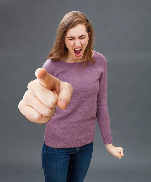 Розлючена молода жінка кричить, вказуючи боса на великий палець — стокове фото