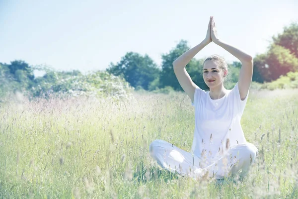 Sorrindo jovem mulher ioga sentado com as mãos acima de sua cabeça — Fotografia de Stock