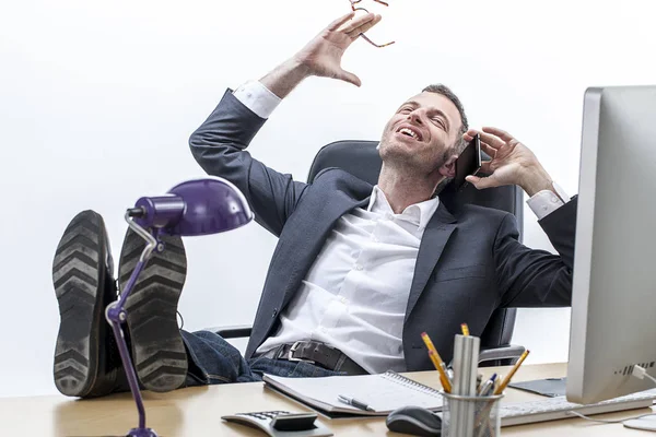 Super mužský podnikatel s nohama na stole smíchem na telefonu — Stock fotografie