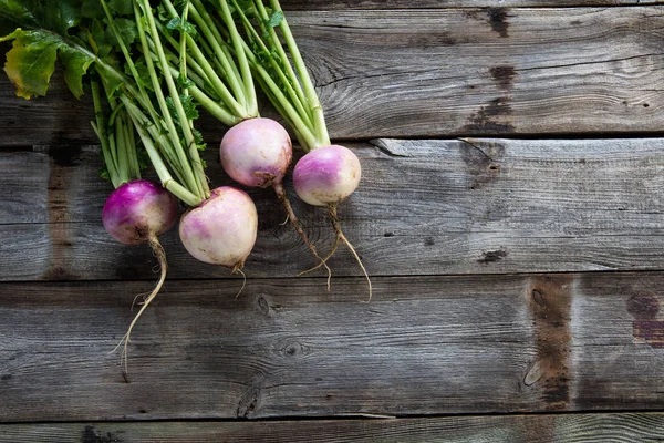Imperfect organic turnips, fresh green tops on authentic wood background — Stock Photo, Image