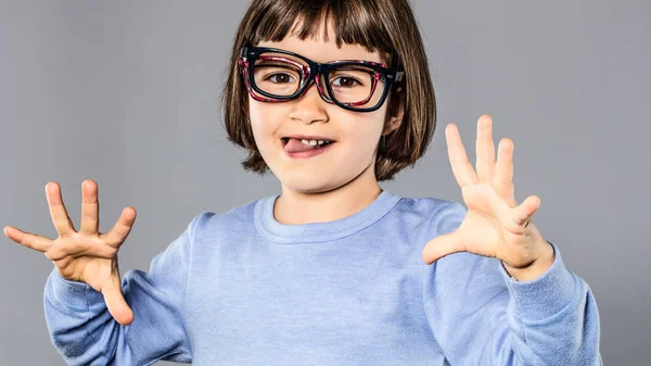 Joyful young child wearing many eyeglasses playing, making funny face — Stock Photo, Image