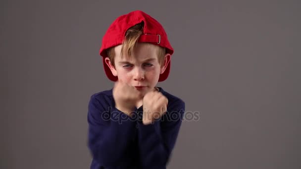 Violento niño pequeño con sombrero de vuelta amenazando o defendiéndose — Vídeos de Stock