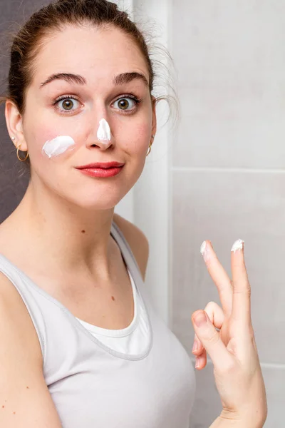 Playful beautiful girl acting surprised with fun moisturizing face cream — Stock Photo, Image