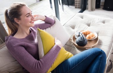 Rahatlamak için Avrupa kahvaltı ile oturan mutlu genç kadın sabah