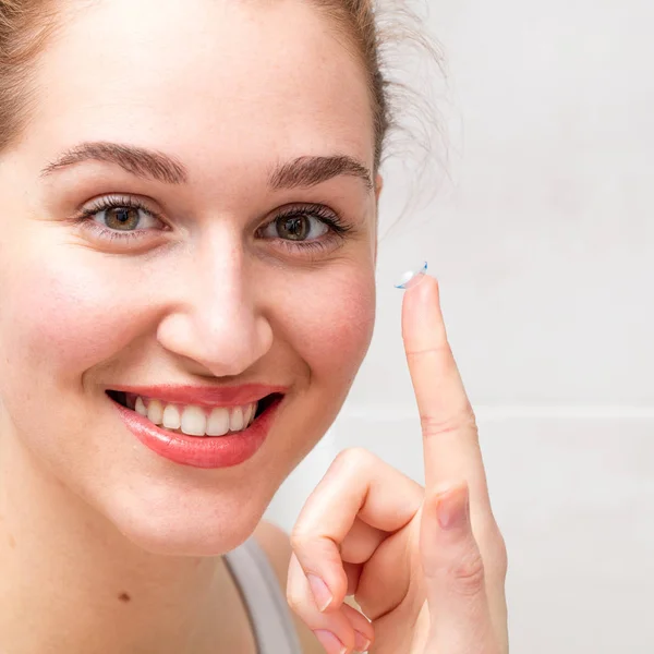 Retrato de una joven hermosa sonriente sosteniendo una lente de contacto —  Fotos de Stock