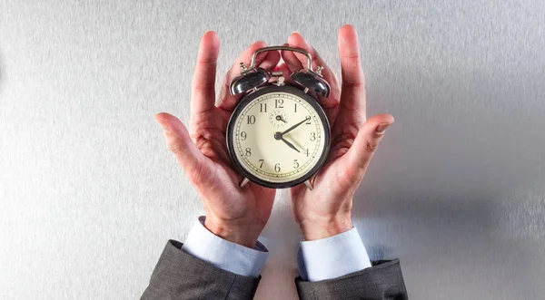 surprised businessman hands holding an alarm clock for time strategy