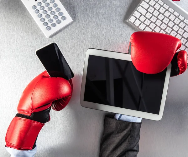 frustrated businessman hands with boxing gloves multitasking with digital tablet