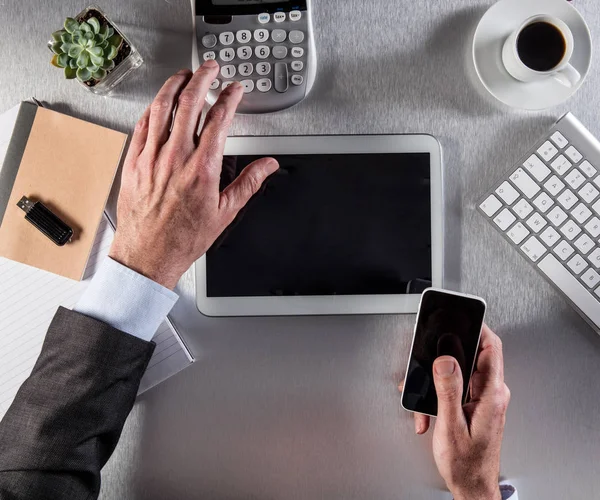 businessman hands counting on digital tablet and calculator on desk