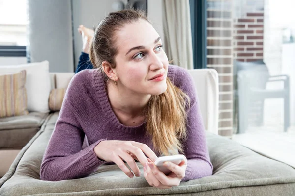 Soñando hermosa mujer joven acostada con teléfono inteligente e imaginación — Foto de Stock