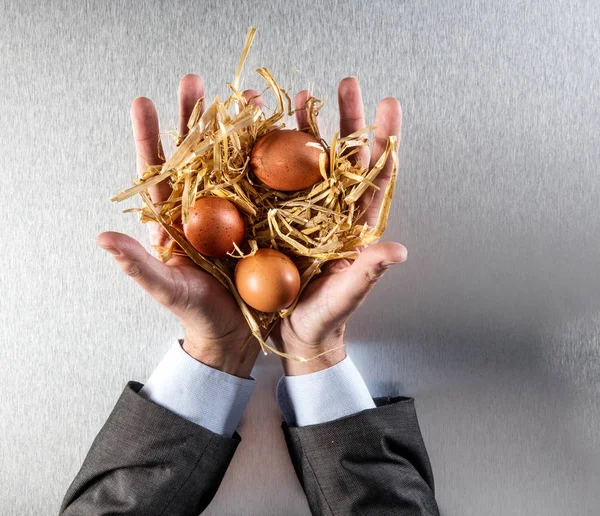 Руки бізнесмена, що представляють стійкі яйця в соломі для збереження їжі — стокове фото