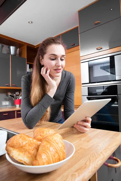 Happy beautiful girl standing reading her home tablet at home — Stock Photo, Image