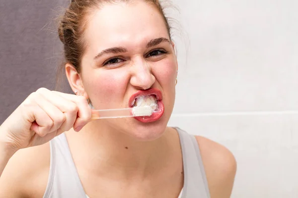 Агрессивная здоровая стоматологическая помощь красивой молодой женщине в ванной комнате — стоковое фото