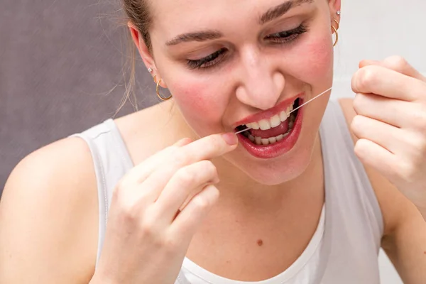 Κοντινό πλάνο του όμορφη νεαρή γυναίκα, χρησιμοποιώντας οδοντικό νήμα για υγειονομική περίθαλψη — Φωτογραφία Αρχείου