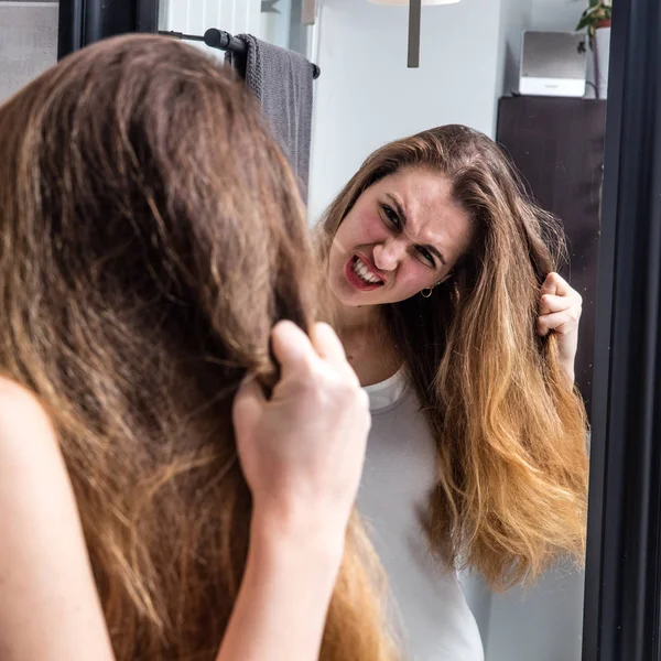 Enfurecida joven mujer sacando su seco pelo largo — Foto de Stock