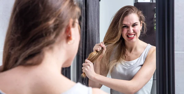 Joven enojada sacando su largo cabello enredado seco — Foto de Stock