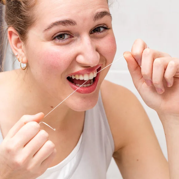 Крупный план счастливой красивой молодой женщины с зубной нитью — стоковое фото