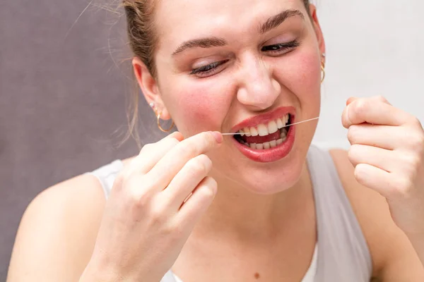 Молодая женщина поранилась при использовании зубной нити для гигиены — стоковое фото