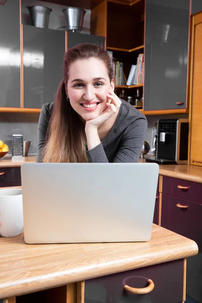 Feliz hermosa joven en su cocina usando su computadora — Foto de Stock