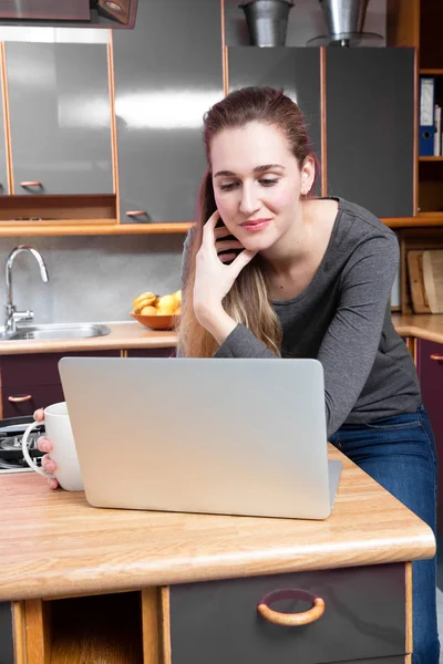 Concepto de casa de trabajo - pensando joven hermosa mujer leyendo en el ordenador portátil — Foto de Stock