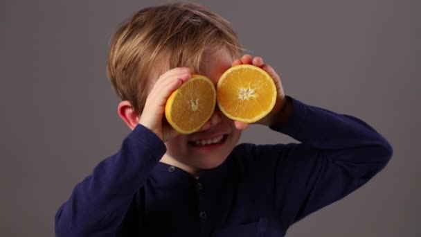 Kıkırdayarak güzel genç çocuk turuncu ile oynarken iyimserlik için koruyucu gözlük — Stok video