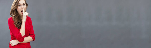 stunned playful girl asking for discretion with finger on mouth