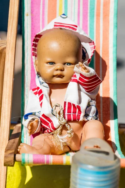 Красивая старая летняя кукла на маленьком шезлонге для детской ностальгии — стоковое фото