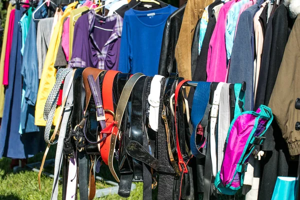 Muitos cintos e roupas de adulto no rack na venda de garagem — Fotografia de Stock