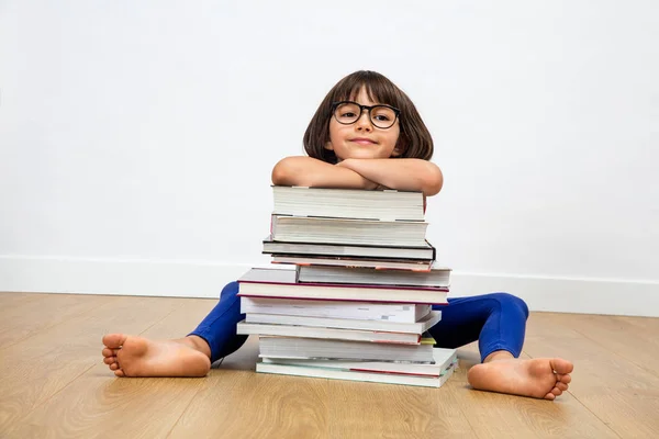 Niño de primaria sonriente con anteojos apoyados en un montón de libros —  Fotos de Stock