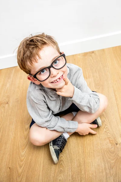 Lachende begaafde jongen met slimme brillen en tand ontbrekende gezeten — Stockfoto