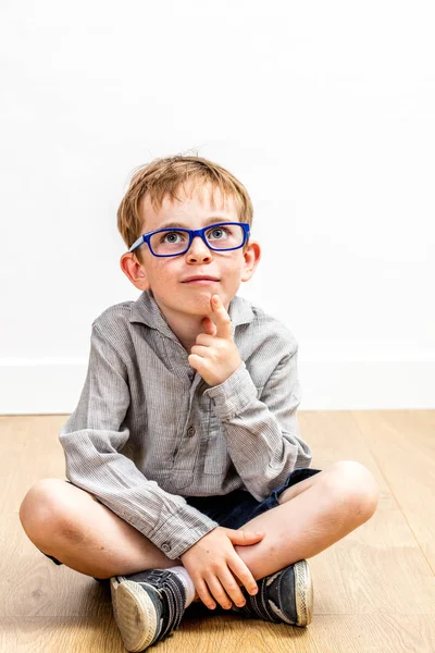 Mosolygó fiú gondolkodás, a gyermek-ártatlanság szemüvegek portréja — Stock Fotó