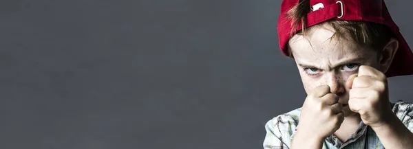 Загрозливий хлопчик з веснянками і червоним капелюхом виглядає жорстоко, банер — стокове фото
