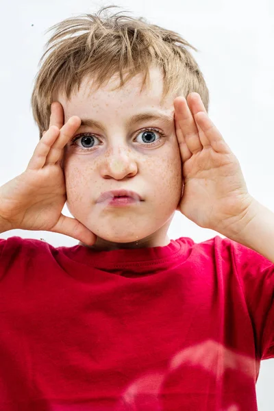 Lekfull liten pojke att göra en krossad grimas, röra vid hans ansikte — Stockfoto