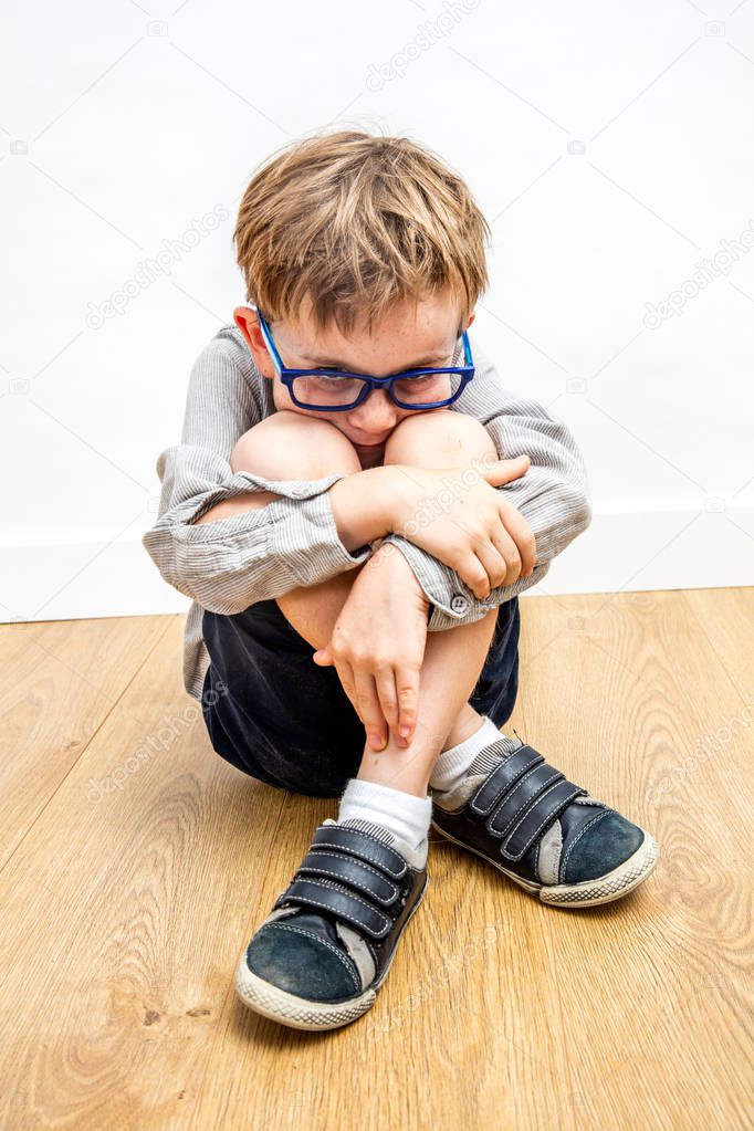 scared child with eyeglasses and protective body language against bullying