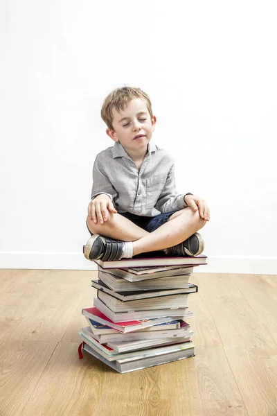 Χαμογελαστό γαλήνιο αγόρι διαλογίζεται κάθεται πάνω από τα βιβλία mindfulness — Φωτογραφία Αρχείου