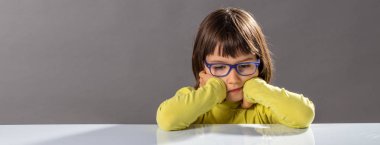 unhappy confused child with eyeglasses thinking, feeling sad or bored clipart